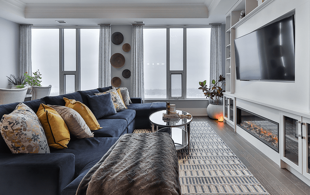 просторен хол от апартамент със син диван, голям телевизор и камина